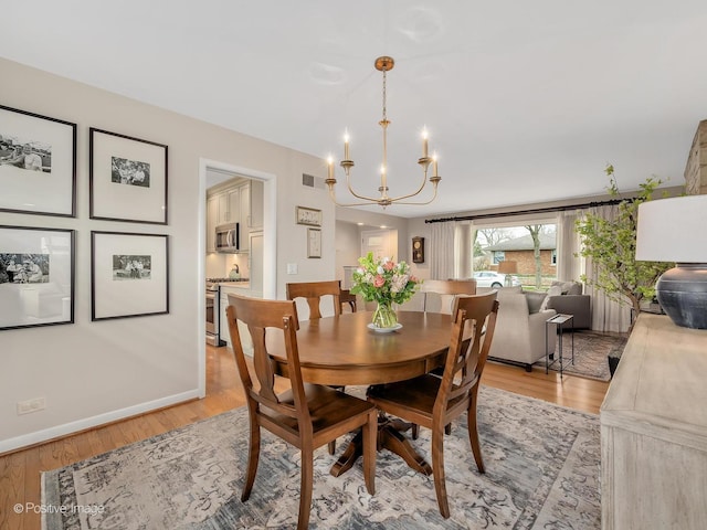 dining area featuring a chandelier, light wood finished floors, and baseboards