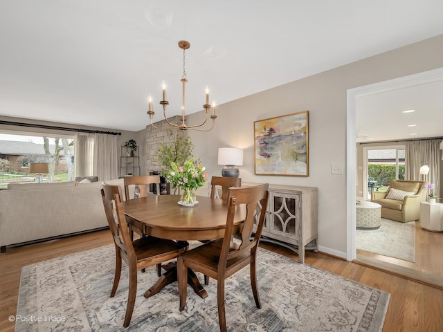 dining room with plenty of natural light, a chandelier, wood finished floors, lofted ceiling, and baseboards