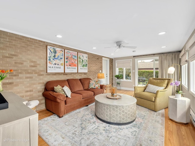 living area with brick wall, light wood-style floors, a ceiling fan, and recessed lighting