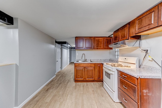1230 S 57th Ct, Cicero, IL 60804 - kitchen with white gas stove, under cabinet range hood, a sink, light wood-style floors, and light countertops