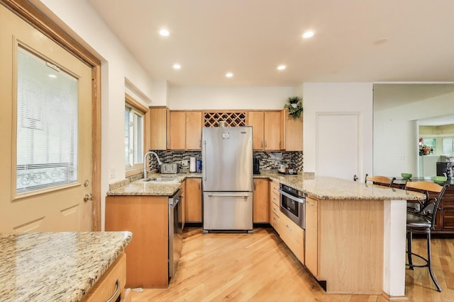 6911 N Wildwood Ave, Chicago, IL 60646 - kitchen featuring stainless steel appliances, a sink, a peninsula, light wood-type flooring, and recessed lighting