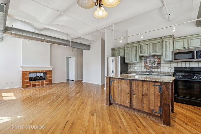 kitchen featuring stainless steel appliances, track lighting, green cabinets, baseboards, and backsplash