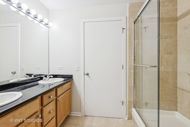 full bath with a stall shower, tile patterned flooring, double vanity, and baseboards