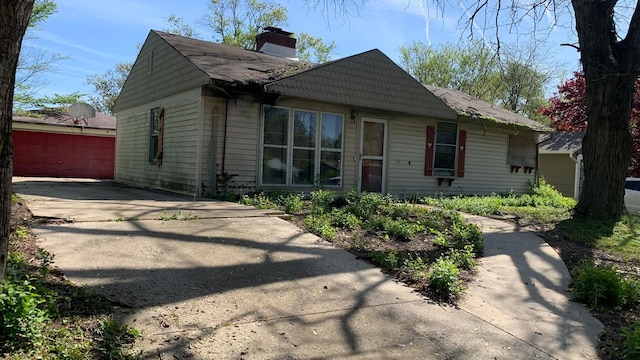 view of front of property featuring an outbuilding, a chimney, and a detached garage