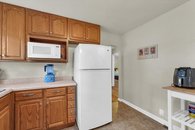505 S Maple St, Urbana, IL 61801 - kitchen featuring white appliances, brown cabinetry, light countertops, and baseboards