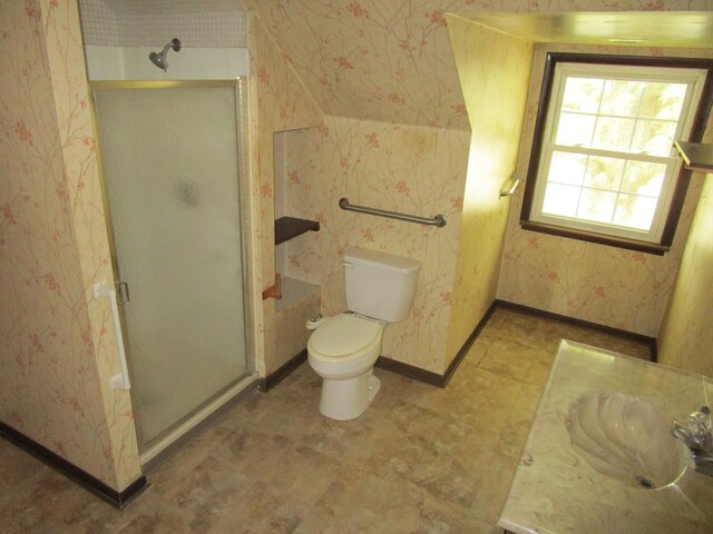 bathroom featuring a stall shower, wallpapered walls, a sink, baseboards, and toilet