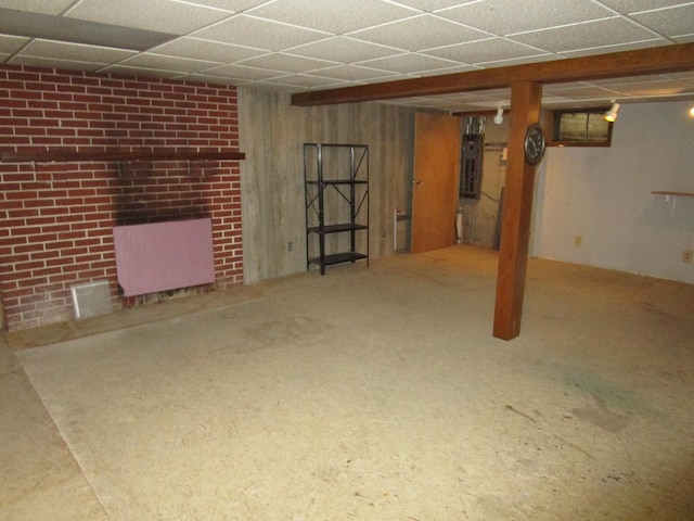 finished below grade area featuring a drop ceiling, carpet flooring, and electric panel