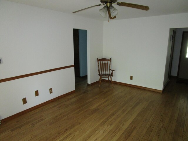 spare room featuring wood-type flooring, a ceiling fan, and baseboards