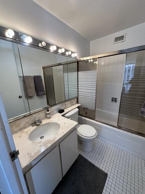 bathroom with vanity, tile patterned flooring, enclosed tub / shower combo, and toilet