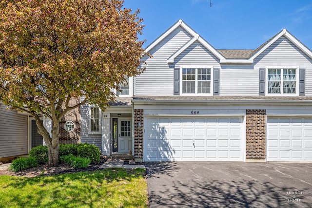 view of front of property with an attached garage, brick siding, asphalt driveway, and a shingled roof