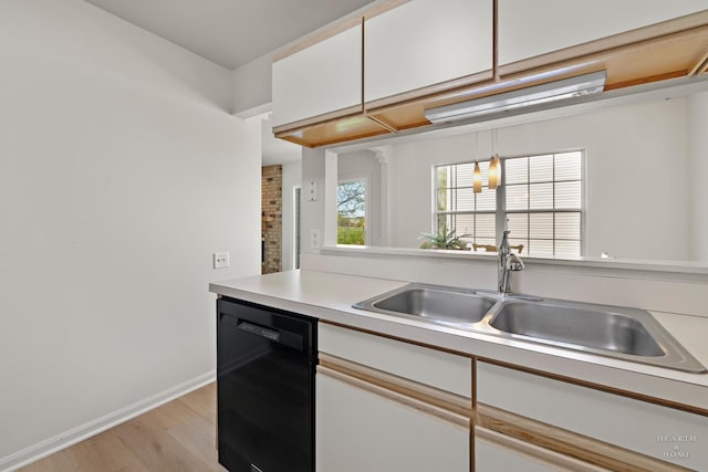 kitchen featuring dishwasher, light wood-style flooring, light countertops, a sink, and white cabinetry