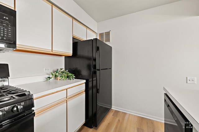 kitchen featuring black appliances, light countertops, light wood-type flooring, white cabinets, and baseboards