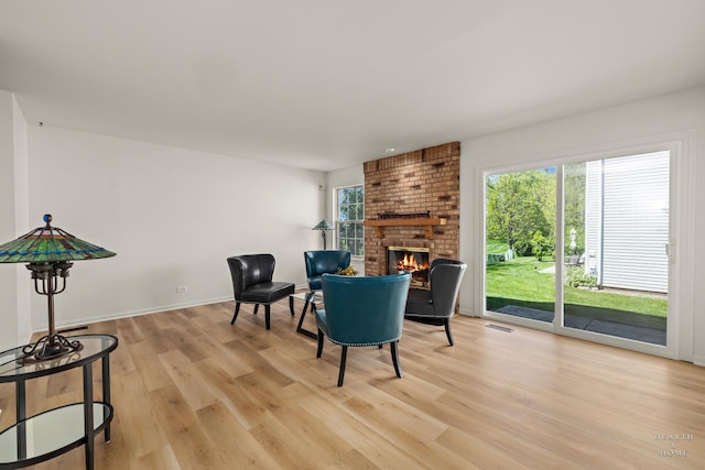sitting room featuring light wood finished floors, a fireplace, and baseboards