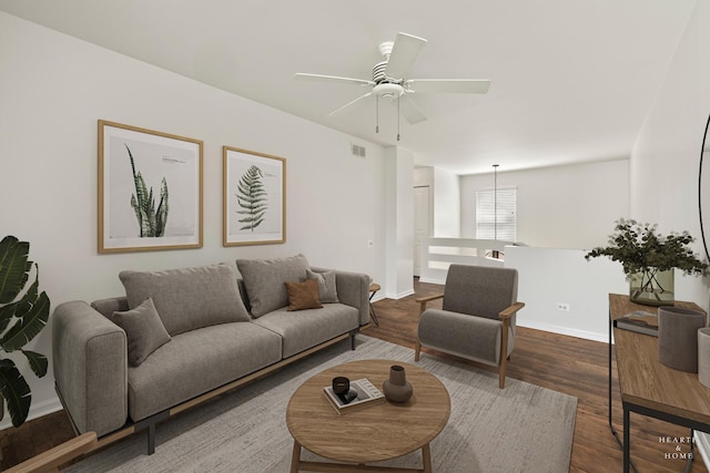 living area featuring dark wood-style floors, a ceiling fan, and baseboards