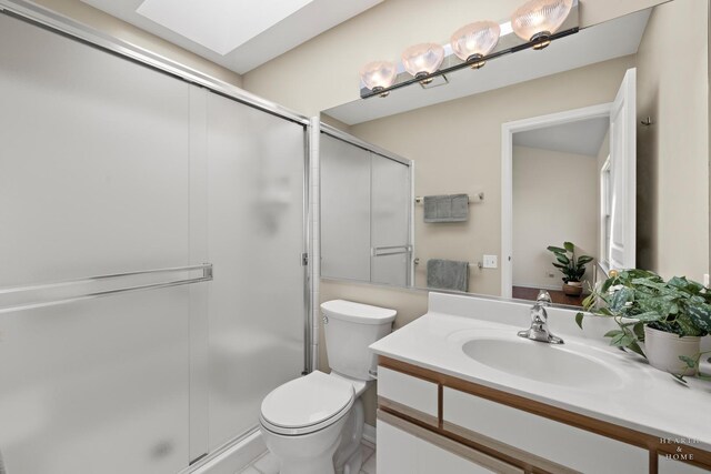 bathroom with a shower stall, vanity, toilet, and a skylight