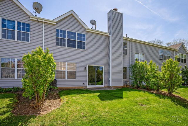 rear view of property with a chimney and a lawn