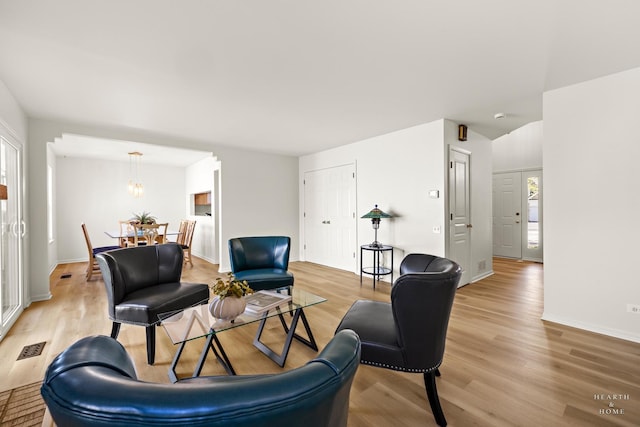 living room featuring light wood finished floors, a chandelier, and baseboards