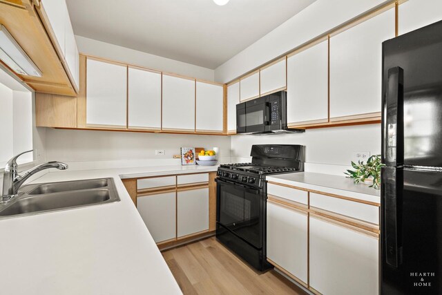 kitchen featuring black appliances, a sink, light countertops, and light wood-type flooring