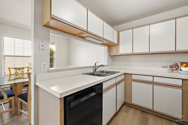 kitchen with dishwasher, a sink, light wood-style flooring, and light countertops