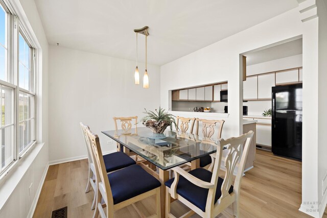 dining room featuring light wood finished floors and baseboards