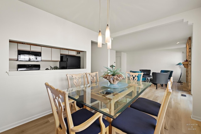 dining space featuring wood finished floors, baseboards, and beamed ceiling