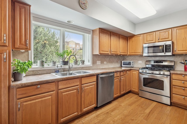 5155 Madison St Unit 204, Skokie, IL 60077 - kitchen featuring appliances with stainless steel finishes, a sink, light wood-style flooring, decorative backsplash, and plenty of natural light