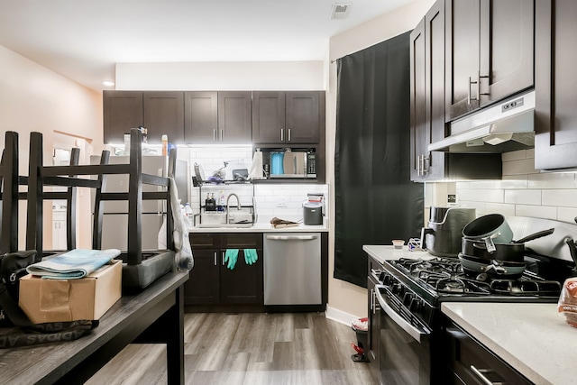 9841 S Ewing Ave, Chicago, IL 60617 - kitchen with appliances with stainless steel finishes, under cabinet range hood, a sink, tasteful backsplash, and light countertops