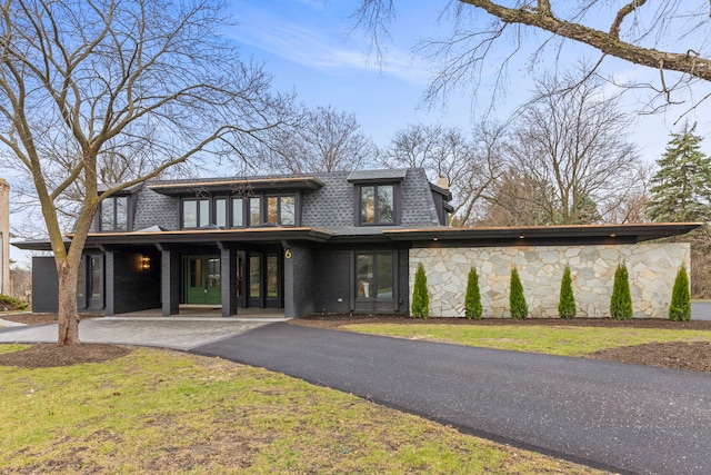 view of front of home featuring mansard roof, a shingled roof, stone siding, asphalt driveway, and french doors