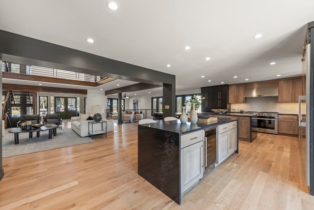 kitchen featuring stainless steel range, wine cooler, wall chimney exhaust hood, recessed lighting, and a kitchen island
