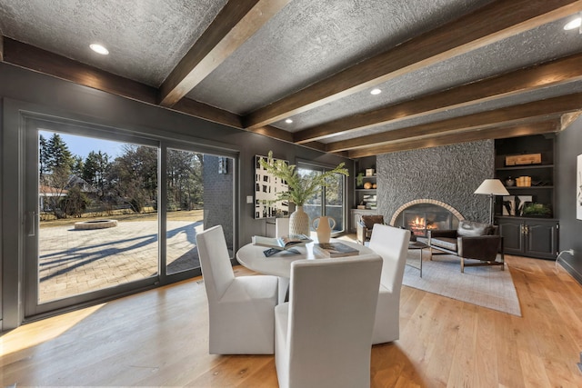 dining area with hardwood / wood-style floors, beamed ceiling, a tile fireplace, recessed lighting, and built in features