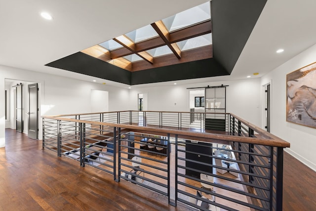 corridor featuring a skylight, wood finished floors, baseboards, coffered ceiling, and recessed lighting