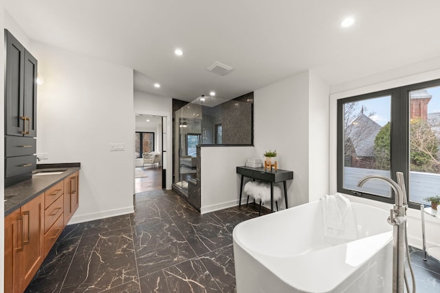 full bathroom with marble tiled floors, recessed lighting, vanity, a freestanding bath, and walk in shower