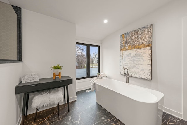 full bathroom with marble tiled flooring, recessed lighting, a freestanding tub, and baseboards