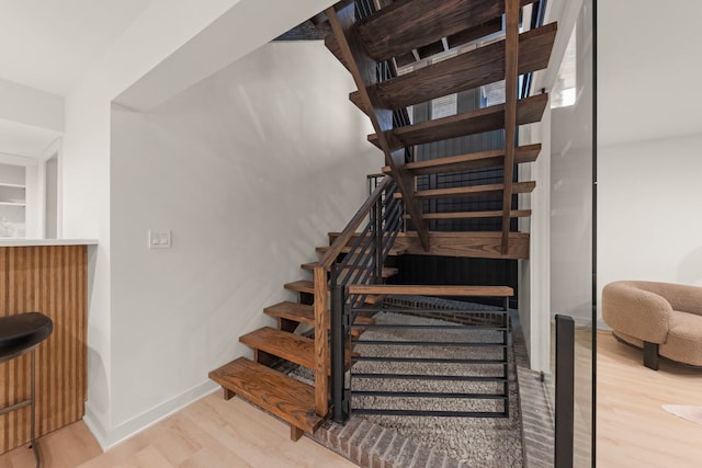stairway with wood finished floors and baseboards