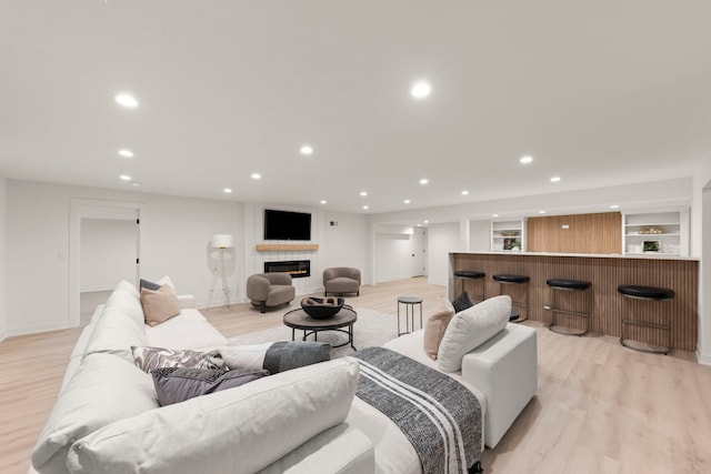 living area featuring a dry bar, light wood finished floors, recessed lighting, a tiled fireplace, and baseboards