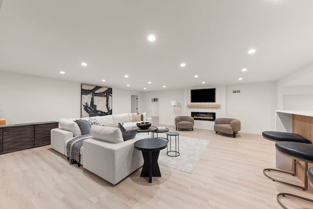 living room with a tile fireplace, recessed lighting, light wood-style flooring, and baseboards