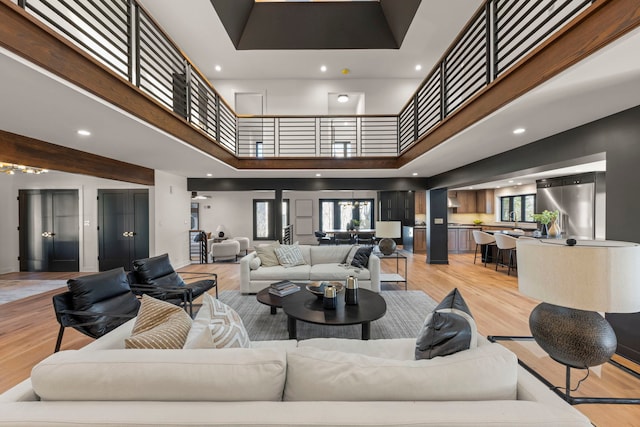 living area featuring healthy amount of natural light, light wood-style floors, a high ceiling, and recessed lighting