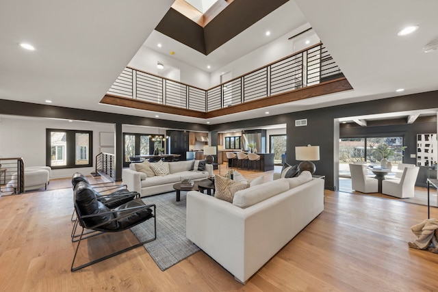 living room with wood finished floors, recessed lighting, a high ceiling, and baseboards
