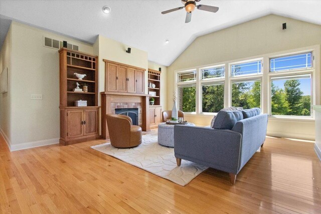 2297 Deer Ridge Ct, Carlock, IL 61725 - living room featuring healthy amount of natural light, a tiled fireplace, light wood finished floors, and lofted ceiling