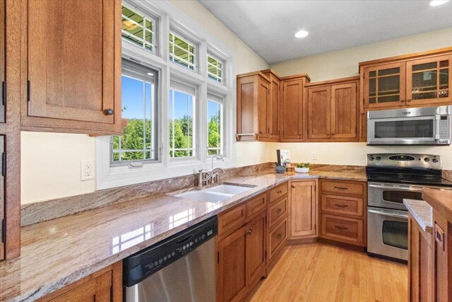 2297 Deer Ridge Ct, Carlock, IL 61725 - kitchen with appliances with stainless steel finishes, a sink, brown cabinetry, light wood-type flooring, and light stone counters