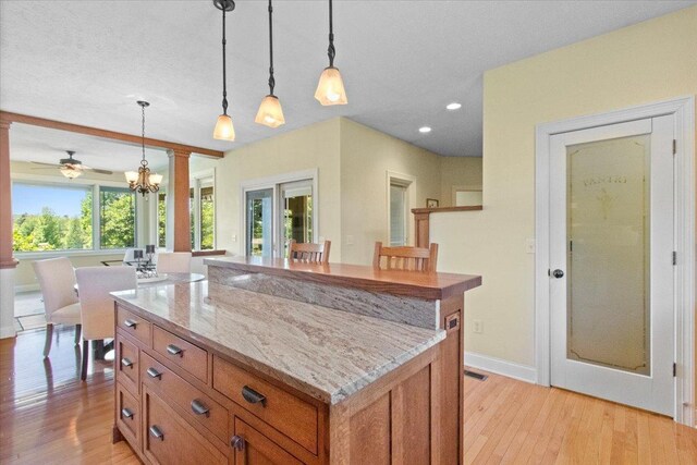 2297 Deer Ridge Ct, Carlock, IL 61725 - kitchen with brown cabinets, light wood-style flooring, french doors, decorative light fixtures, and light stone counters