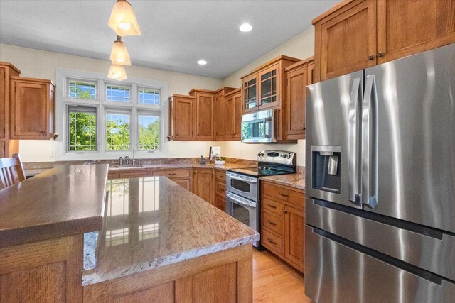2297 Deer Ridge Ct, Carlock, IL 61725 - kitchen with appliances with stainless steel finishes, brown cabinetry, light stone counters, glass insert cabinets, and recessed lighting