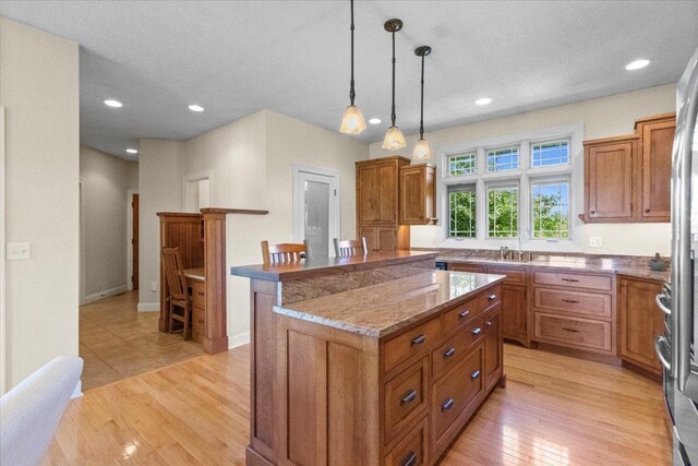 2297 Deer Ridge Ct, Carlock, IL 61725 - kitchen featuring brown cabinets, light stone counters, a kitchen island, light wood-style floors, and recessed lighting