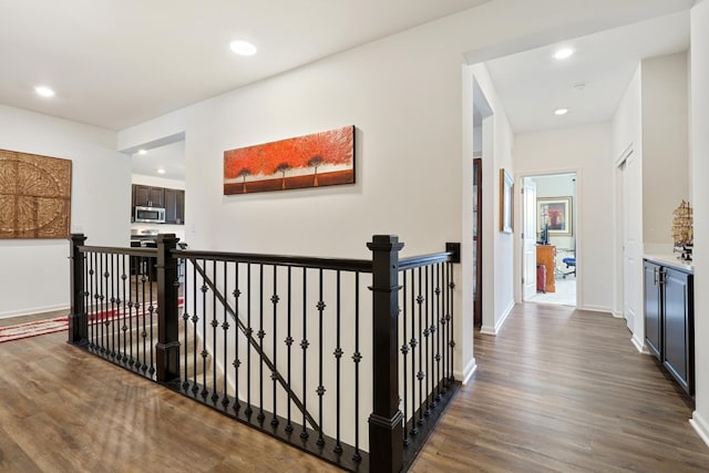 hall featuring an upstairs landing, dark wood finished floors, recessed lighting, and baseboards