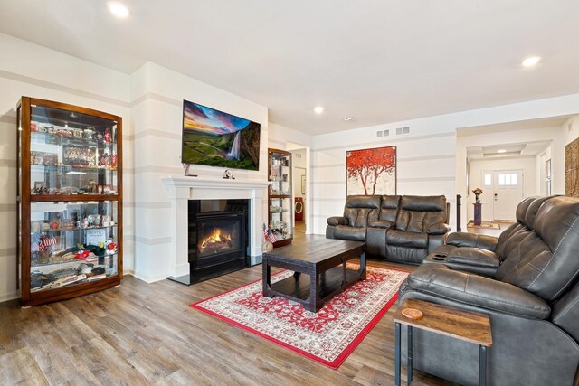 living area with wood finished floors, a glass covered fireplace, and recessed lighting