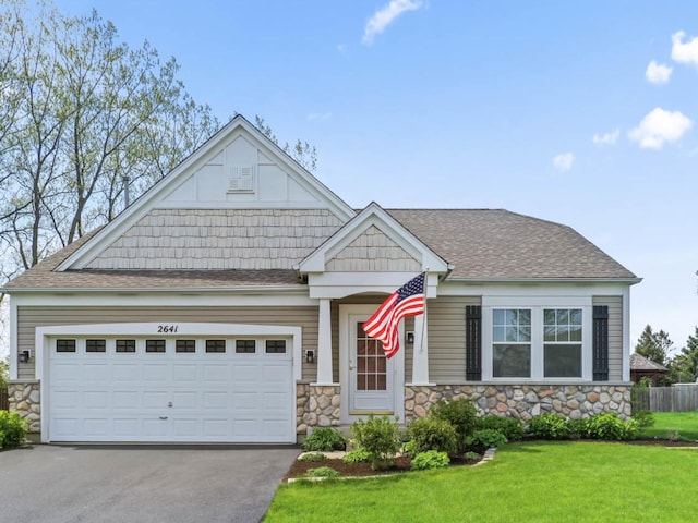 craftsman inspired home featuring stone siding, driveway, a front yard, and an attached garage