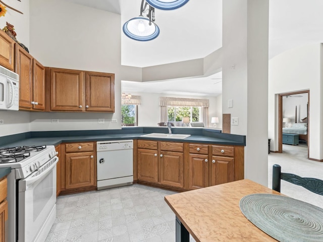 kitchen featuring white appliances, a sink, high vaulted ceiling, brown cabinets, and dark countertops