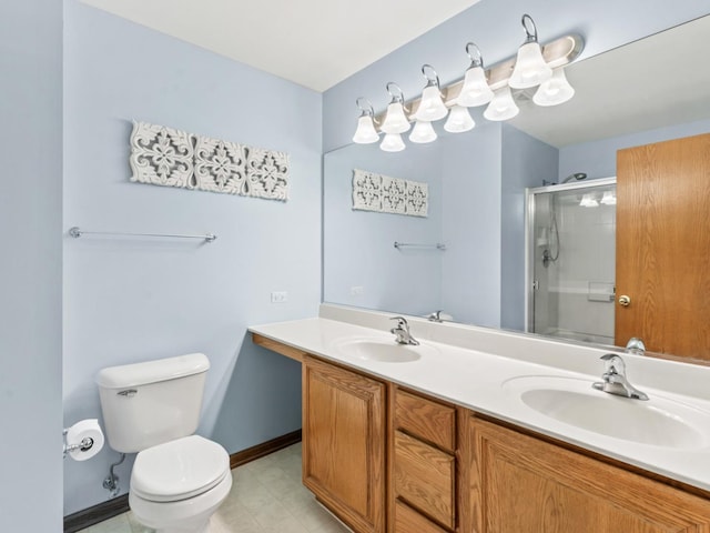 bathroom featuring toilet, a shower with door, double vanity, and baseboards