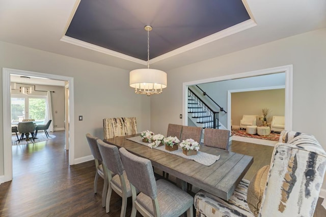 dining area with a raised ceiling, a chandelier, stairway, dark wood-type flooring, and ornamental molding