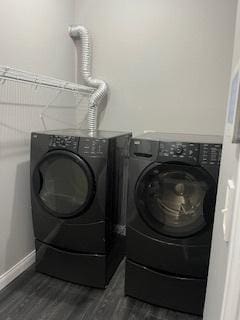 washroom with washing machine and dryer, dark wood-type flooring, and baseboards